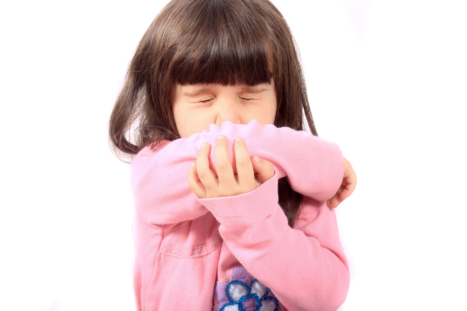 Little sick girl sneezing onto her sleeve