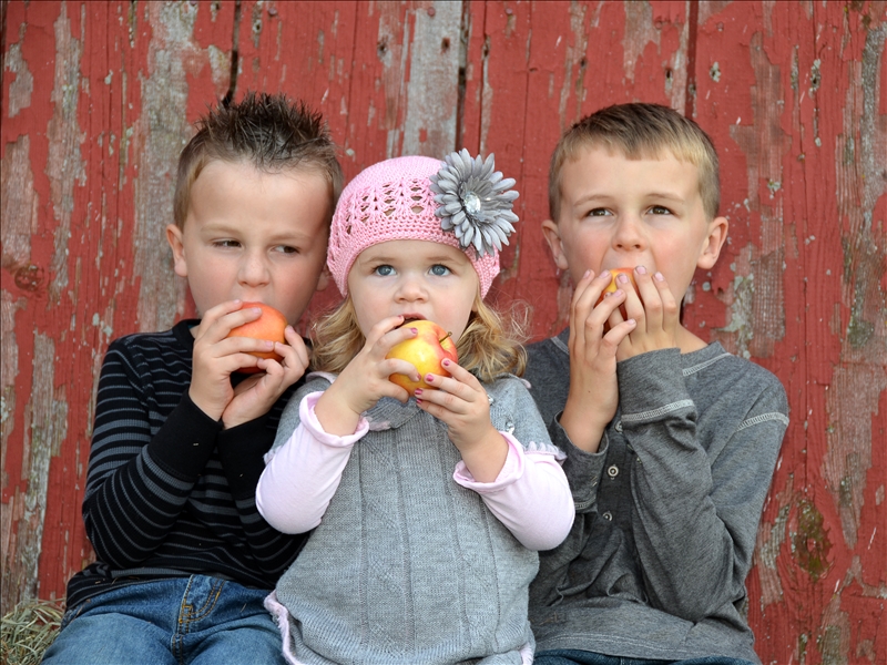 Three children eating apples