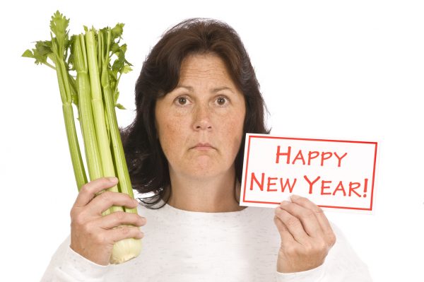 Unhappy woman showing celery and happy new year sign/resolutions