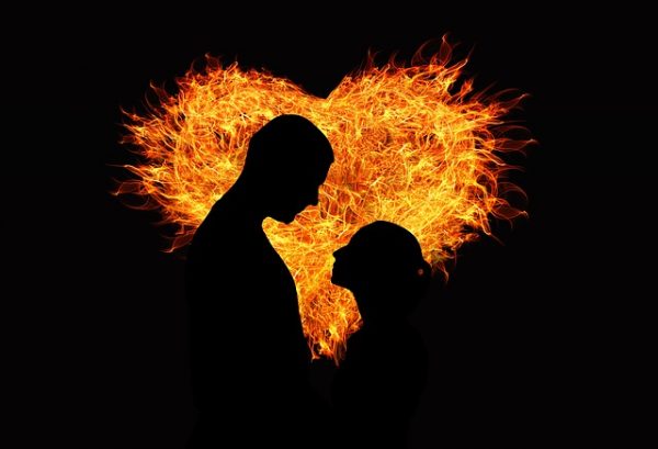 Silhouette of two people against a flaming heart of love