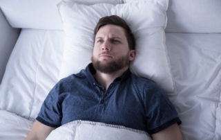 man suffering from insomnia lying in bed