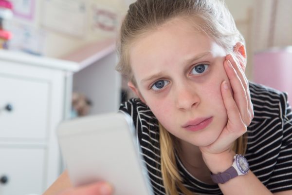 Young girl looking at phone/cyberbullying