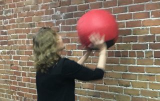 Diane Atwood slamming medicine ball against the wll/exercise