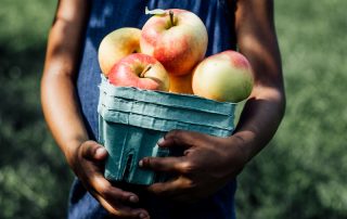 Person holding container of apples