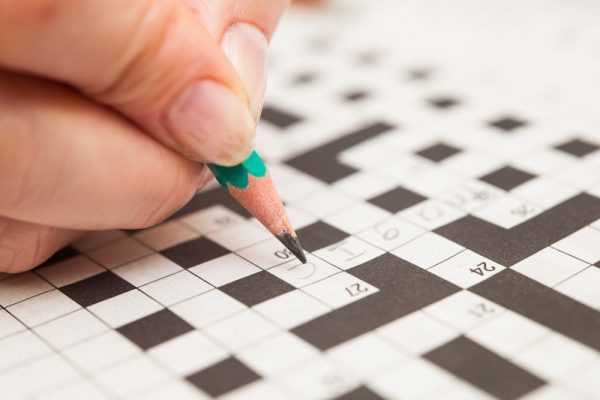 person doing crossword puzzle/Adobe stock